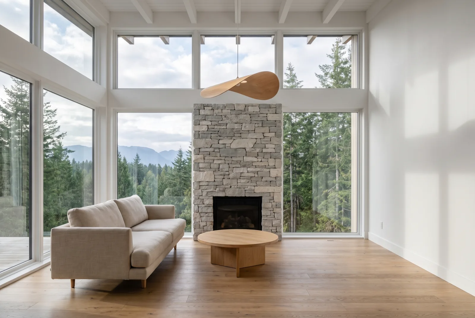 Interior walkthrough frame of a bright living room with a stone fireplace and floor-to-ceiling windows